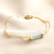 Green Aventurine Charm Chain Bracelet in Gold laid out on top of beige coloured fabric