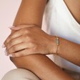 Model wearing Green Aventurine Charm Chain Bracelet in Gold with hand on arm against pink backdrop