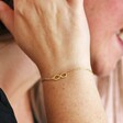 Close Up of Model Wearing Infinity Charm Bracelet in Gold