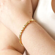 Model wearing Rectangular Beaded Bracelet in Gold with hand on arm