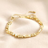 Rectangular Beaded Bracelet in Gold laid out on top of beige fabric