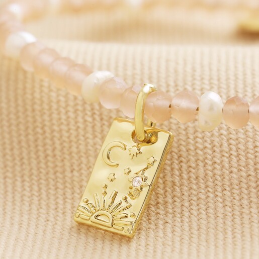 Close Up of Talisman Charm Pink and Pearl Beaded Bracelet in Gold on Beige Fabric