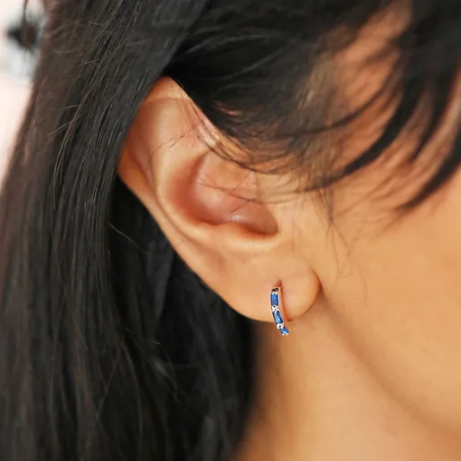 Close up of Blue Baguette Crystal Huggie Hoops in Silver on model