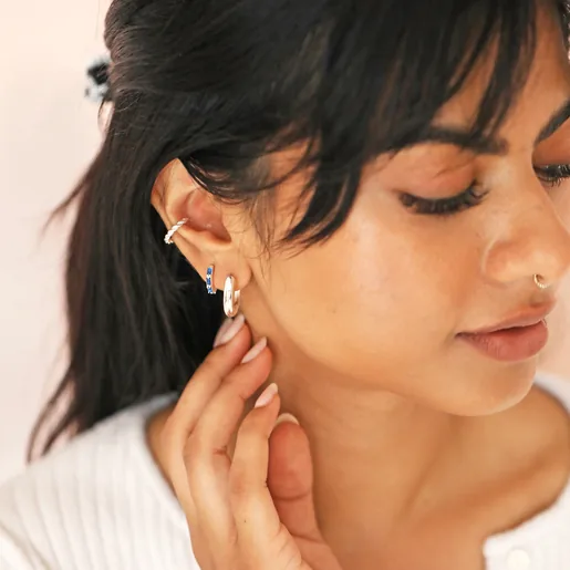 Blue Baguette Crystal Huggie Hoops in Silver on model with hand on neck