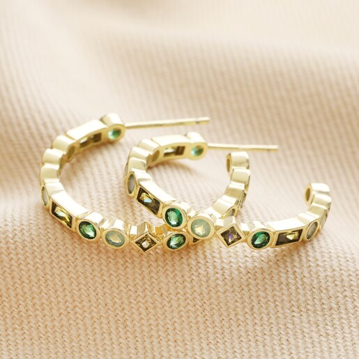 Hoops from Set of 2 Green Crystal Huggie and Hoop Earrings in Gold laid out on neutral coloured fabric