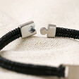 Close up of clasp on Men's Leather Fishtail Bracelet in Black on top of neutral coloured material
