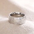 Men's Stainless Steel Textured Wide Band Ring on top of neutral coloured material