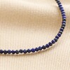 Close up of Delicate Blue Stone Beaded Necklace on Beige Fabric