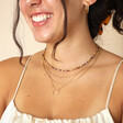 Model wearing the Delicate Brown Stone Beaded Necklace layered with other gold necklaces