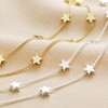 Double Chain and Star Charm Necklace in Silver next to gold version on top of beige fabric