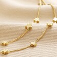Close Up of Charms on Double Chain and Star Charm Necklace in Gold on beige fabric