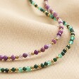 Gold Stainless Steel Stone Bead Necklace in Green laid next to purple version on beige coloured fabric