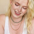 Model smiling wearing curated look with Gold Stainless Steel Stone Bead Necklace in Green with gold chains