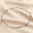Gold Stainless Steel Stone Bead Necklace in Purple on top of beige coloured fabric