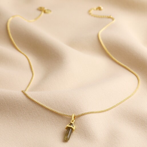 Labradorite Crystal Point Pendant Necklace in Gold Labradorite Crystal Point Pendant Necklace in Gold full length on beige coloured fabric