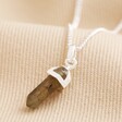 Labradorite Crystal Point Pendant Necklace in Silver on top of neutral coloured surface