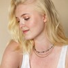 Model looking down wearing Semi-Precious Stone Bead Necklace in Blue and Green against beige coloured backdrop