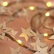 Close up of Battery Powered LED Wooden Star Garland lit up against neutral background