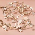 Battery Powered LED Wooden Star Garland arranged against beige coloured surface