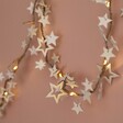 Battery Powered LED Wooden Star Garland hung up on wall against natural coloured background