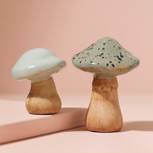 Small Ceramic Toadstool Ornament on top of raised surface next to large size with pink background