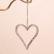 Textured Silver Heart Hanging Decoration Hanging on Branch Against Pink Wall