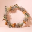 Gingerbread Christmas Wreath Making Kit leaning against beige backdrop