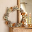 Gingerbread Christmas Wreath Making Kit on top of wooden counter in front of mirror next to bubble candle holder with lit candle