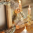 Close up of Gingerbread Christmas Wreath Making Kit on top of wooden counter against mirror with lit candle