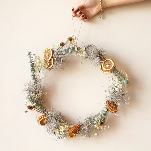 Model holding Gingerbread Christmas Wreath Making Kit against neutral coloured backdrop