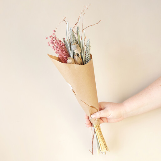 Frosty Berry Dried Flower Bouquet Wrapped in Paper Held Against Wall by Model