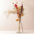 Large Earthly Amber Dried Flowers Letterbox Gift Arranged in a Vase Against a Beige Surface 