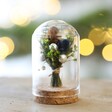 Mini Christmas Dried Flower Glass Dome with blurred Christmas tree in background