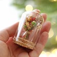 Model Holding Yellow and White Mini Christmas Dried Flower Glass Dome With Christmas Tree and Lights in Background