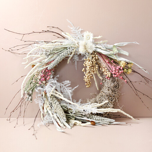 Winter Solstice Dried Flower Wreath Leaning Against Beige Wall