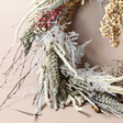 Close up of Florals on the Side of Winter Solstice Dried Flower Wreath Against Beige Background