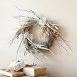 Winter Solstice Dried Flower Wreath Hung On Cream Wall with Wrapped Gifts Underneath