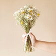 Model holding the Golden Daisy Dream Dried Flower Bouquet against pink background