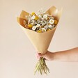 Model holding the Golden Daisy Dream Dried Flower Bouquet wrapped in brown paper