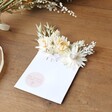 Natural Dried Flower Pocket Buttonhole lying flat on wooden surface next to flowers