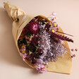 Summer Nights Dried Flower Bouquet wrapped in brown paper lying on surface