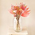 Tutti Frutti Dried Flower Bouquet in a large glass vase on wooden table