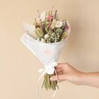 Wildflower Dried Flower Wedding Posy Wrapped in White Paper Held by Model Against Beige Background