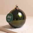 Holly and Fir Tree Glass Bauble Candle on Beige Snow covered Surface