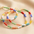 My Doris Set of Three Rainbow Beaded Anklets Stacked Together  on Beige Fabric 