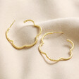 My Doris Etched Flower Hoop Earrings in Gold laid out next to each other on neutral coloured fabric