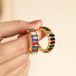 Model holding My Doris Large Rainbow Hoop Earrings in Gold in front of neutral background