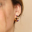 Close up of My Doris Medium Rainbow Hoop Earrings in Gold on model against neutral background