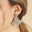 Close up of My Doris Silver Beaded Butterfly Drop Earrings on model against neutral background