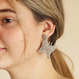 My Doris Silver Beaded Butterfly Drop Earrings on model looking to side against natural coloured backdrop